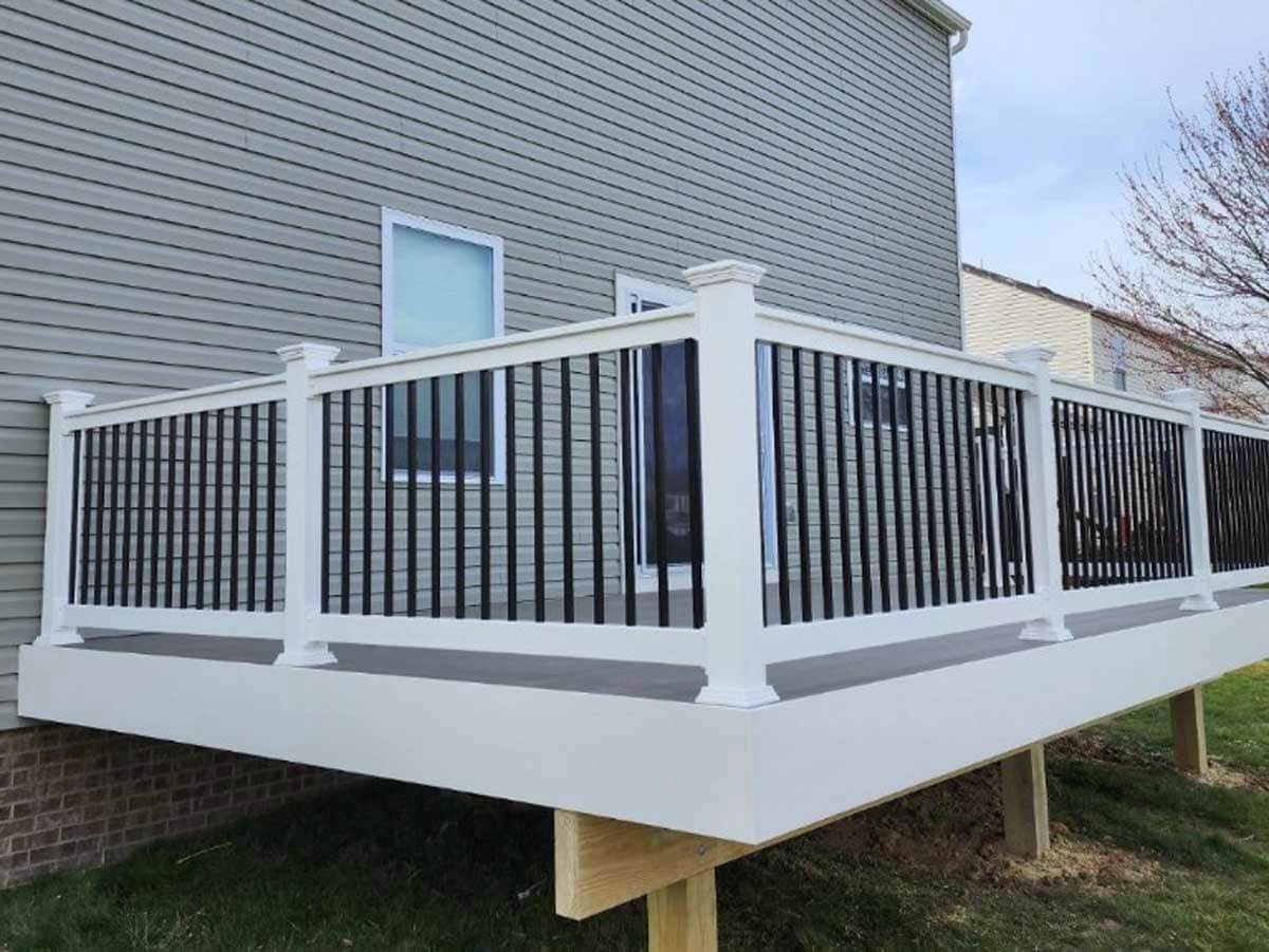 Deck installed on the side of a residential home with aluminum railings that have white posts